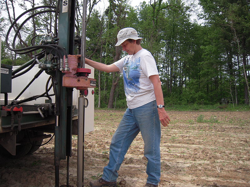 Researcher stands next to a truck-mounted soil probe machine