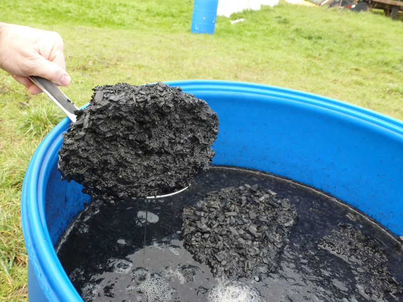 Spoon lifting pile of biochar.