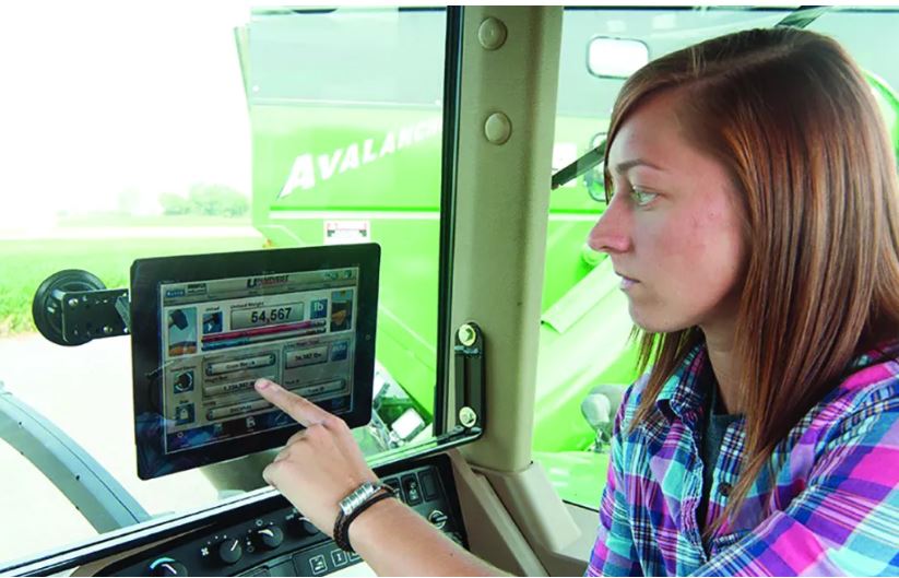 female farmer looking at GPS device inside tractor cab