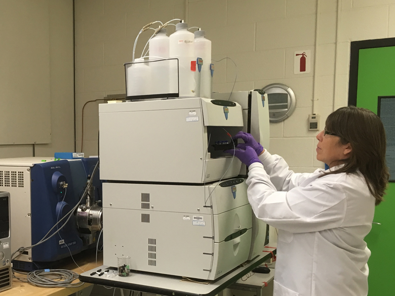 Woman prepares large machine in lab