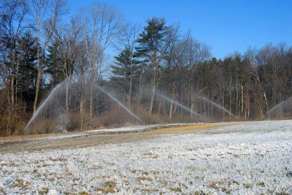 Irrigation sprinklers running on open field.