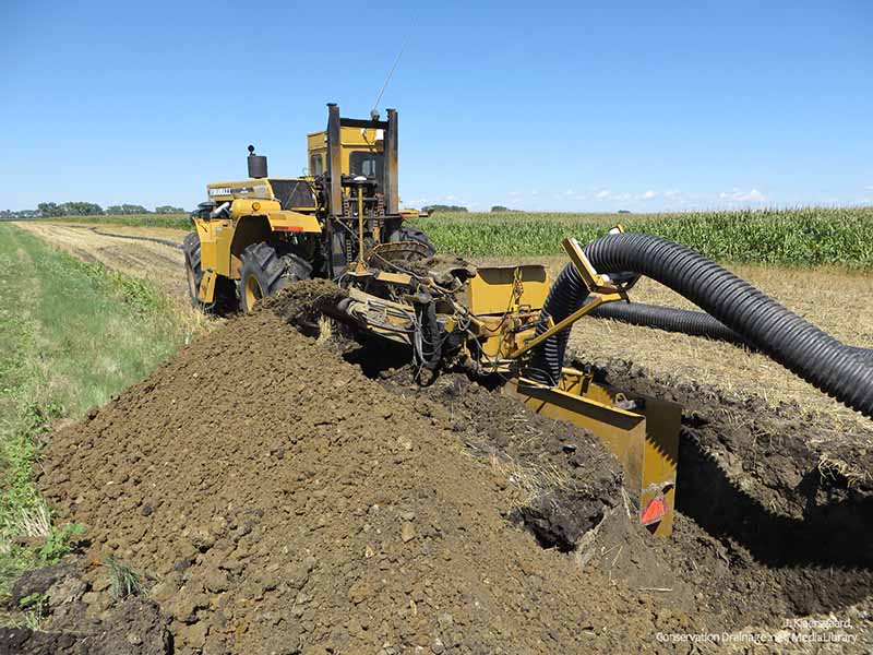 tile drainage trenching machine digging in a field