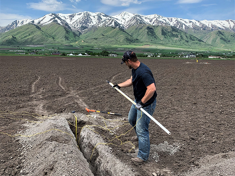 Man in field holding long tube.