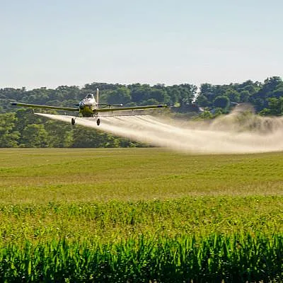 Airplane spraying a field of crops