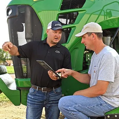 Men standing next to a tractor looking at a tablet